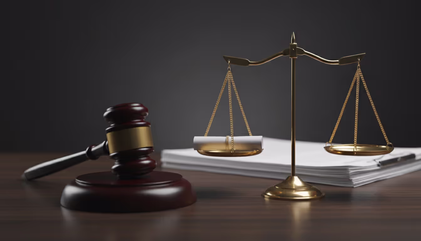 Judges gavel next to legal documents and golden scales of justice with an empty scale on a dark wooden desk